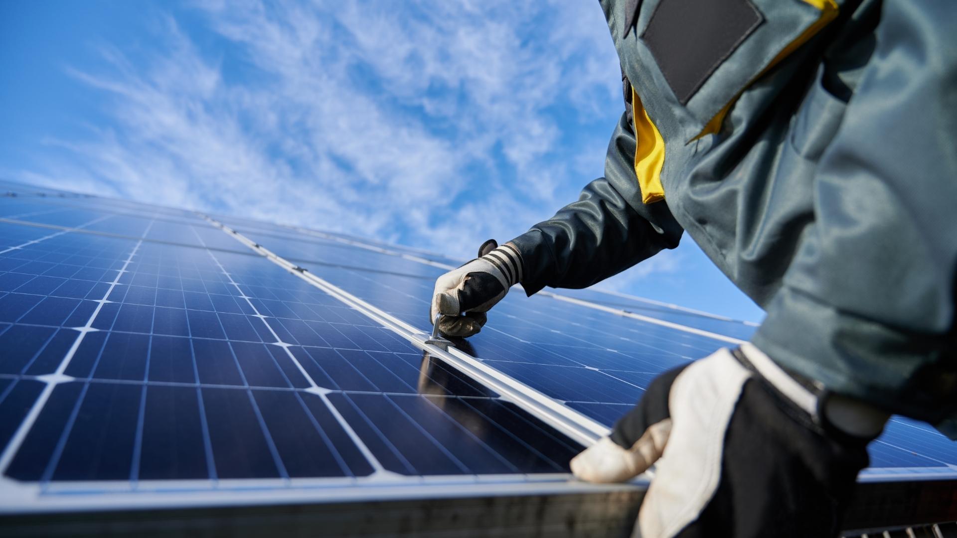 Technician installing solar panels in Cape Town under a clear blue sky, showcasing clean and renewable energy solutions for sustainable electricity generation.
